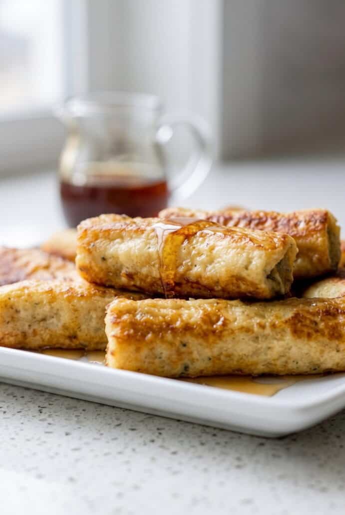 Golden French toast roll-ups served with maple syrup for an easy breakfast.