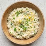 Creamy Parmesan rice topped with parsley and lemon zest in a wooden bowl.