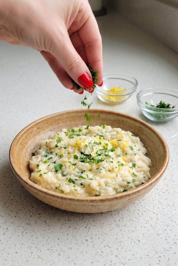Sprinkling fresh parsley over creamy Parmesan rice before serving.