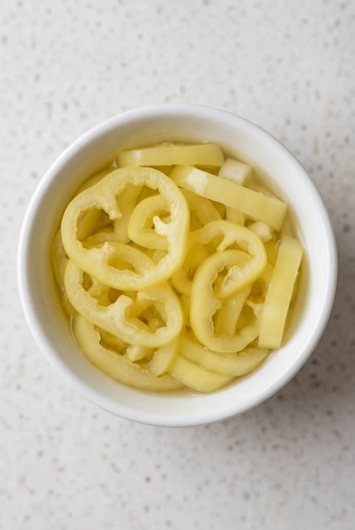 Homemade pickled banana pepper rings served in a small white bowl.