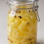 Homemade pickled banana peppers in a glass jar with garlic and whole spices.