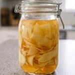 Jar of homemade pickled ginger slices in brine, ready to serve.