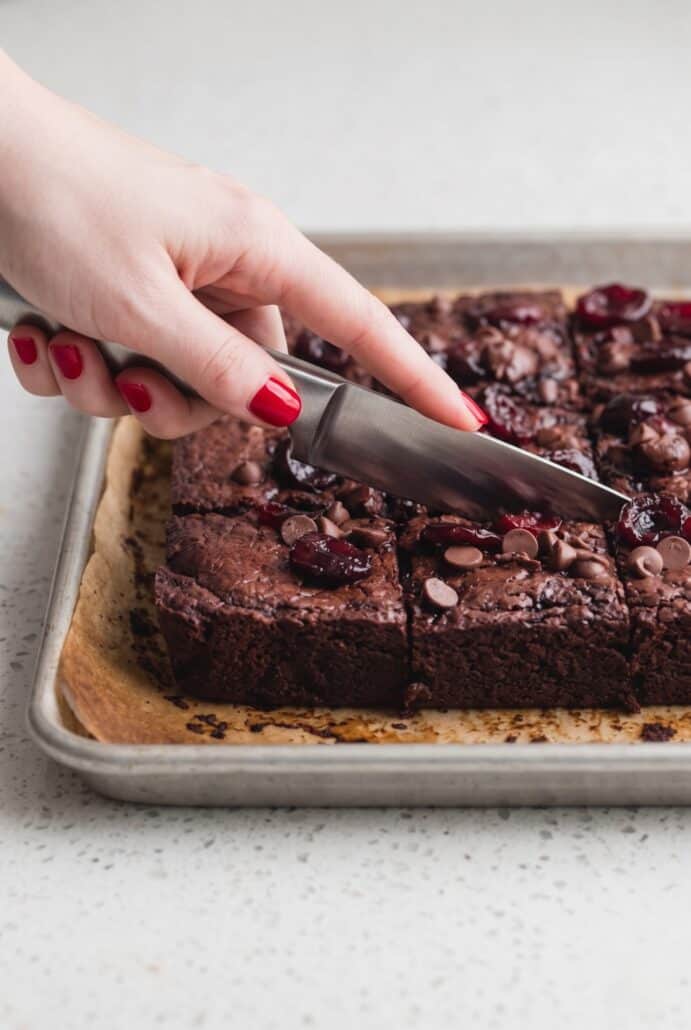 Slicing fudgy roasted cherry brownies into squares after cooling.