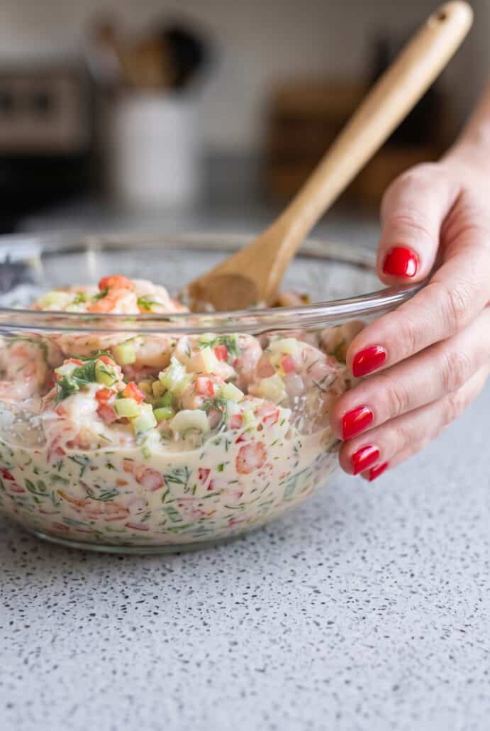 Creamy shrimp salad with dill and vegetables in a glass bowl, ready to serve.