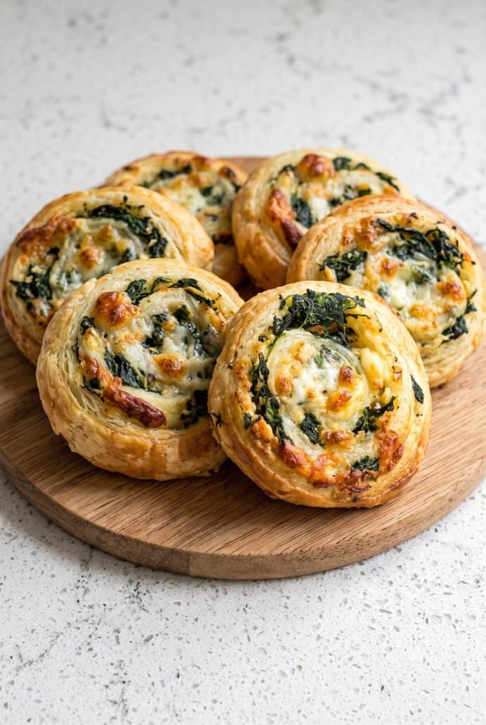 Golden spinach feta puff pastry pinwheels served on a plate as an easy Mediterranean appetizer.