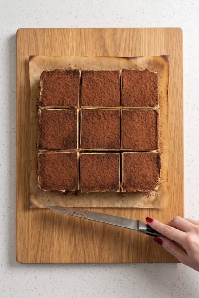 Nine sliced tiramisu brownies with chocolate bases, creamy mascarpone layers, and cocoa-dusted tops.