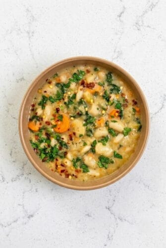 Creamy Tuscan White Bean Soup with Garlic and Herbs Bowl of creamy Tuscan white bean soup with carrots, kale, and herbs, showcasing this hearty one-pot vegetarian soup recipe perfect for a cozy meal.