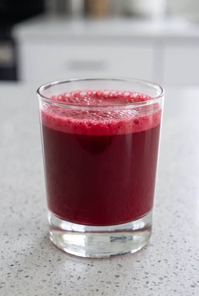 Glass of freshly made watermelon cherry berry beet juice with a foamy top.