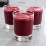 Three glasses of vibrant red homemade fruit juice ready to serve.