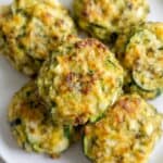 Golden baked zucchini garlic bites served on a white plate.