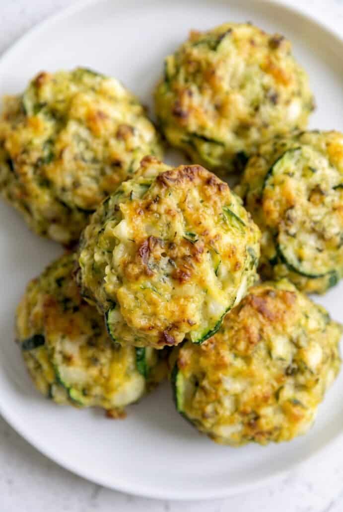 Golden baked zucchini garlic bites served on a white plate.