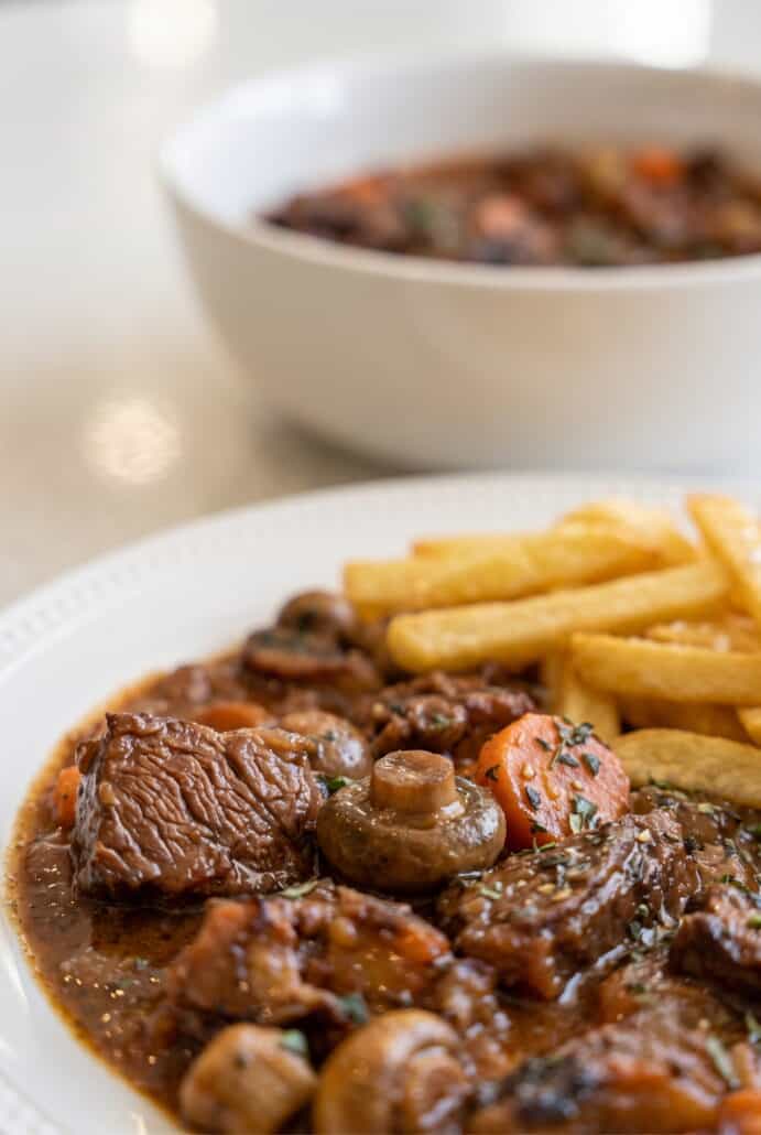 Beef Carbonnade Stew served with crispy fries for a hearty Belgian-style dinner.