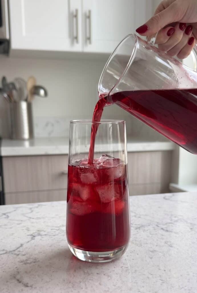 Blueberry lemonade being poured into a glass for a refreshing homemade summer drink.
