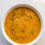 Creamy butternut squash soup garnished with fresh herbs, ready to serve.