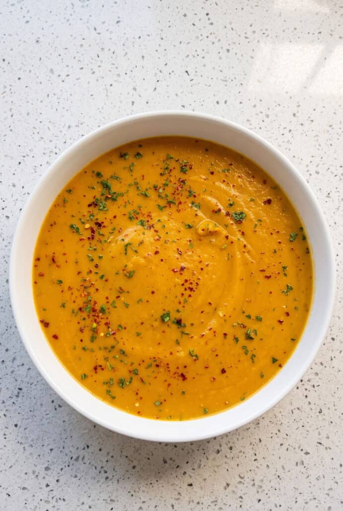 Creamy butternut squash soup garnished with fresh herbs, ready to serve.