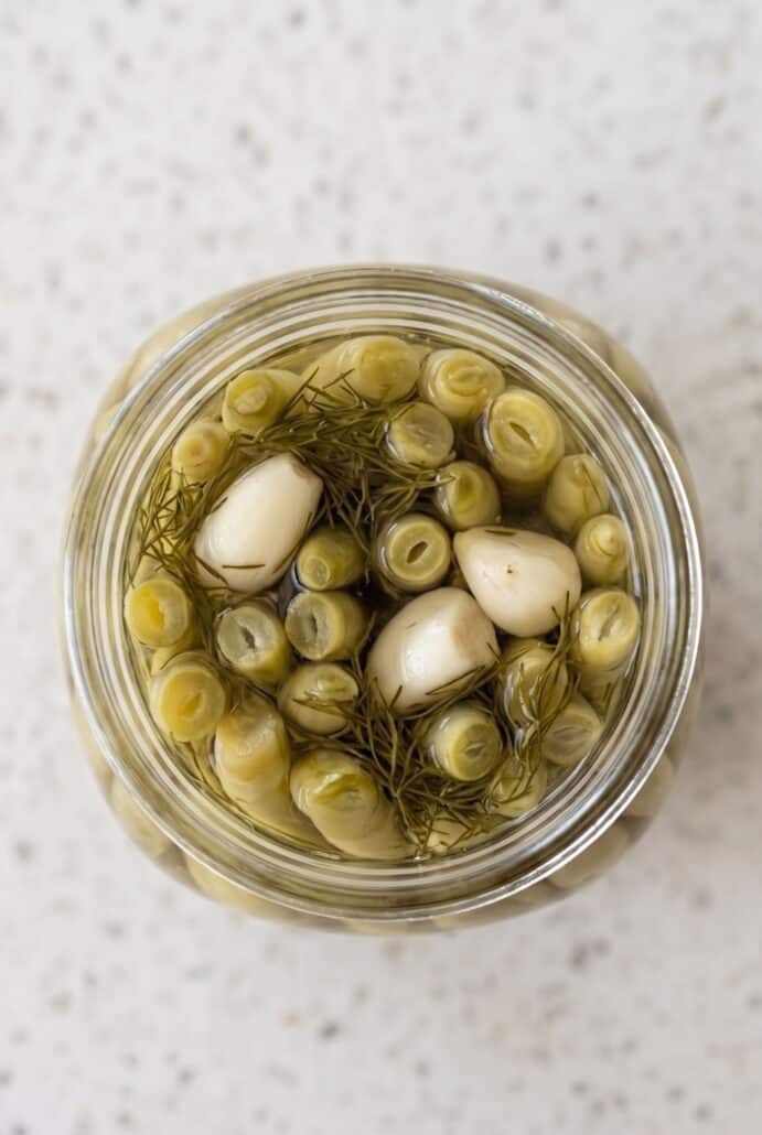 Top view of green beans and garlic packed in a jar for making homemade dill pickled green beans.