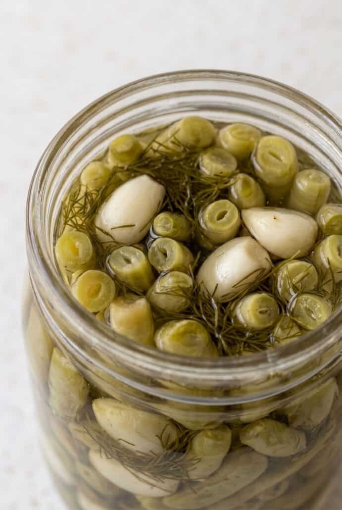 Close-up of green beans and garlic packed in a jar for homemade dill pickled green beans.