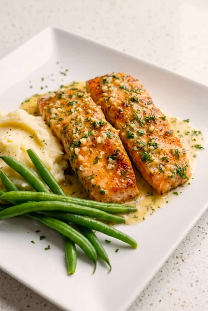Garlic butter salmon fillets topped with fresh herbs.