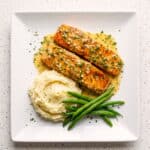 Golden garlic butter salmon fillets garnished with fresh herbs.