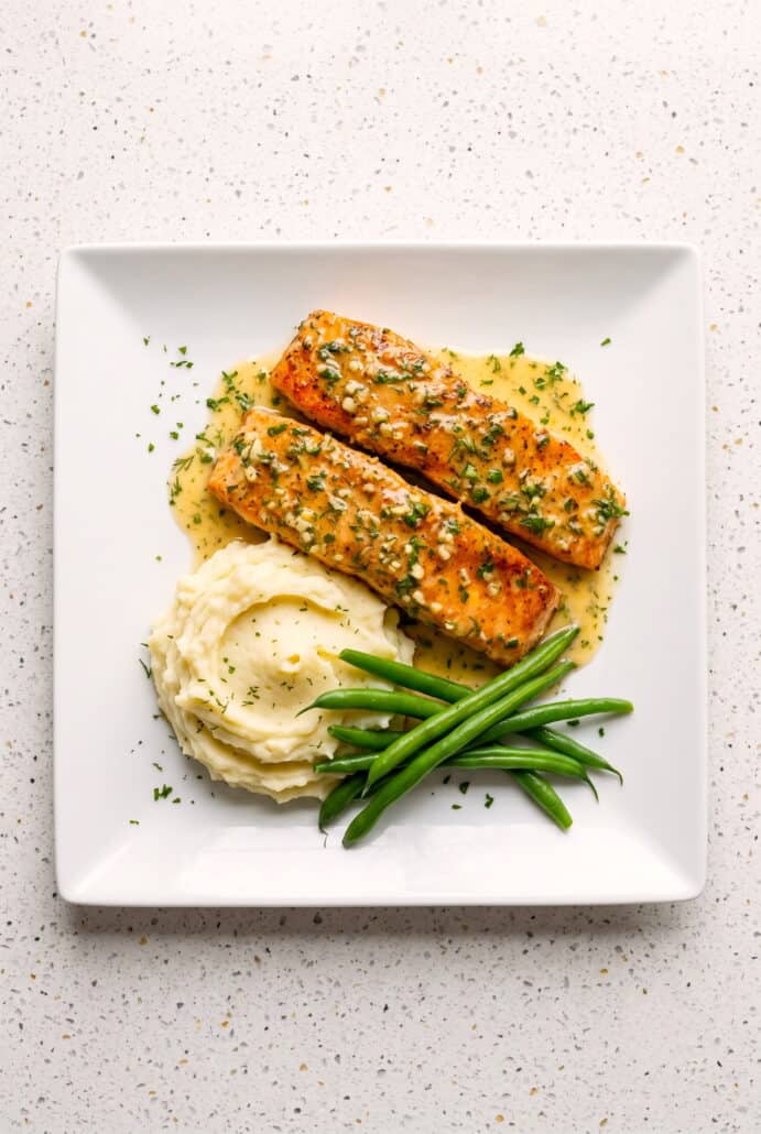 Golden garlic butter salmon fillets garnished with fresh herbs.