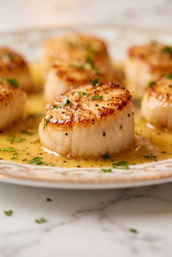 Golden seared garlic butter scallop coated in lemon garlic butter sauce and sprinkled with fresh parsley.