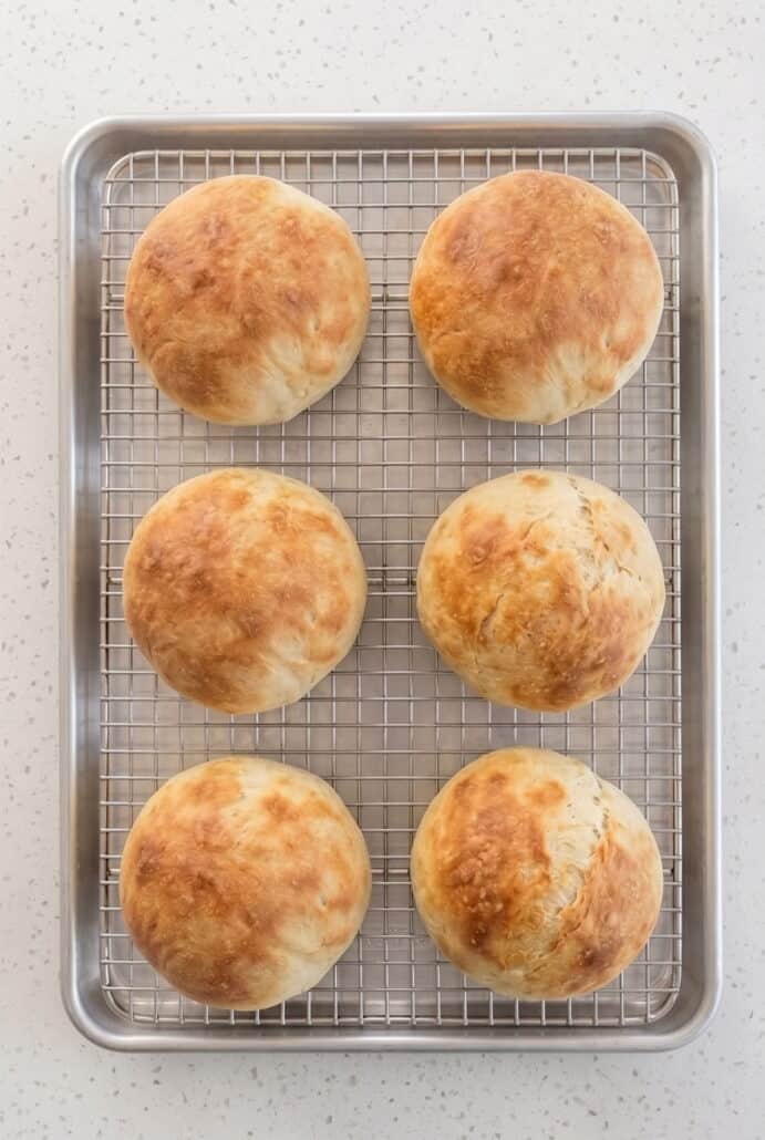 Freshly baked homemade bread bowls cooling on a wire rack until ready to fill with soup.