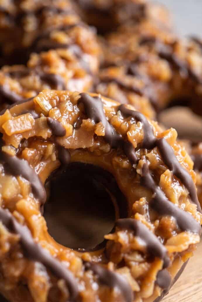 Close-up of a homemade Samoas cookie with gooey caramel, toasted coconut, and chocolate drizzle.