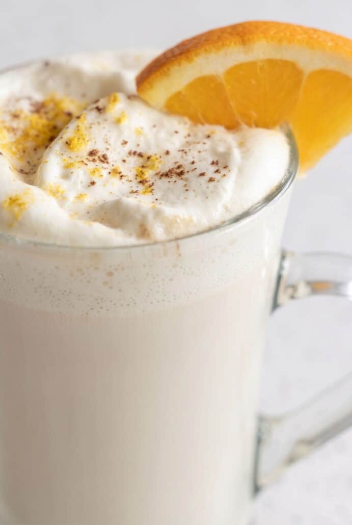 Close-up of white chocolate orange hot cocoa topped with whipped cream, orange zest, and cinnamon.