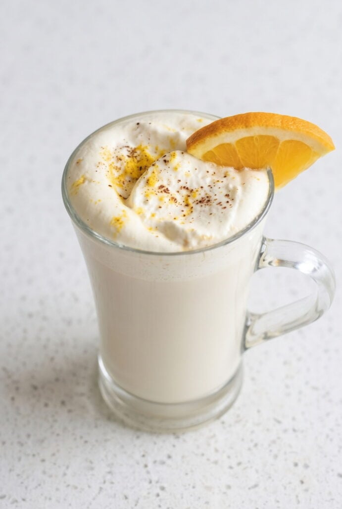 White chocolate orange hot cocoa topped with whipped cream, orange zest, and an orange slice.