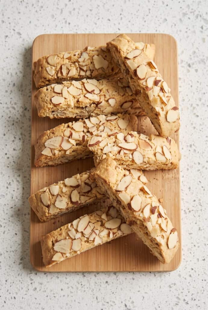 Sliced almond biscotti arranged on a wooden board, showing the crisp texture and almond topping.
