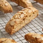 Almond biscotti topped with sliced almonds cooling on a wire rack, ready to serve with coffee or tea.
