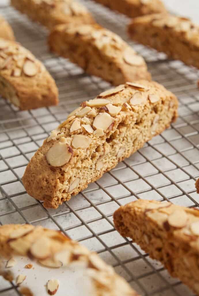 Almond biscotti topped with sliced almonds cooling on a wire rack, ready to serve with coffee or tea.