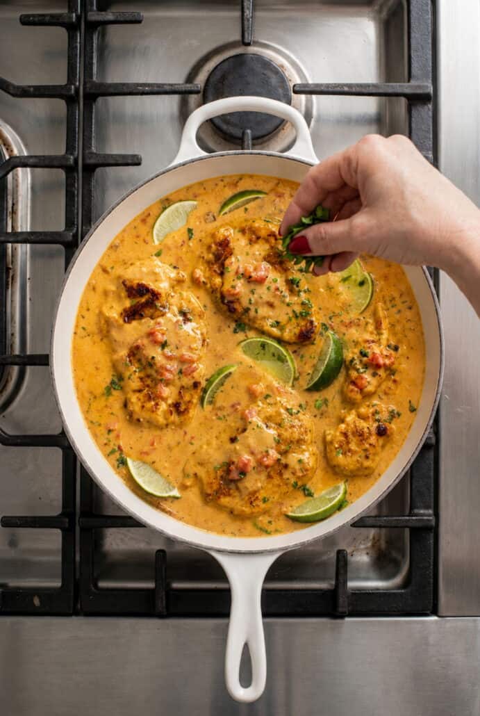 Creamy Cajun chicken simmering in a skillet with lime and herbs.