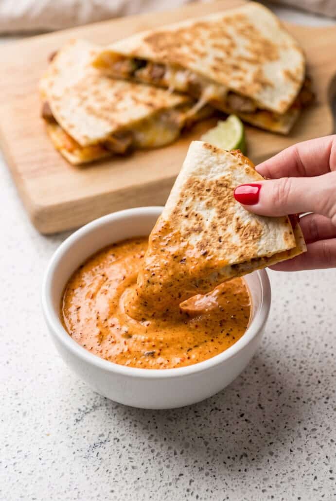 Chip dipped into creamy chipotle garlic sour cream sauce, perfect for serving as an easy appetizer or snack.