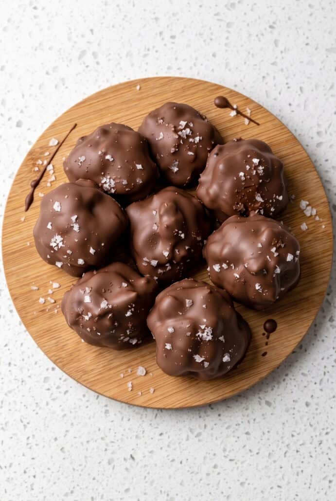 Chocolate-covered strawberry yogurt bites arranged on a wooden serving board.