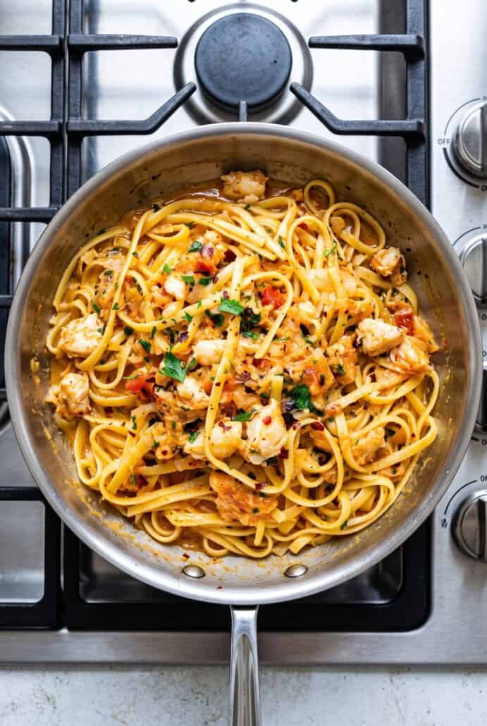 Crab linguine with tender crab meat, tomatoes, parsley, and red pepper flakes cooked together in a skillet.