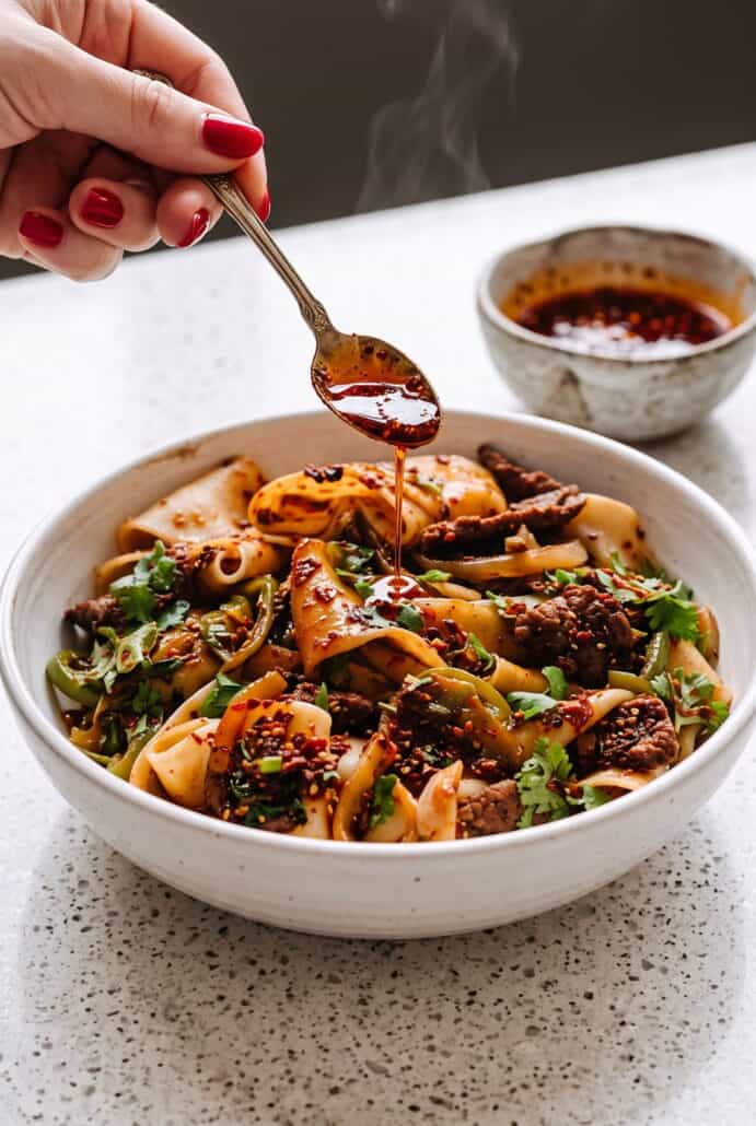 Cumin lamb noodles topped with tender lamb and vegetables, finished with a drizzle of spicy chili oil.