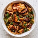Cumin lamb noodles with tender lamb, wide noodles, onions, greens, and spicy chili seasoning.