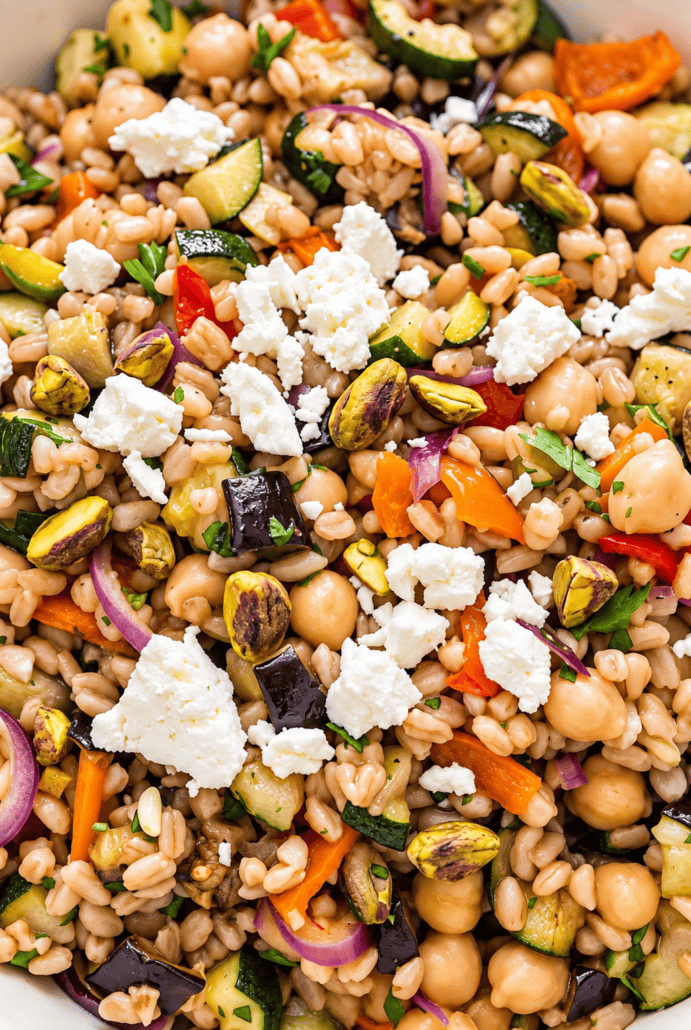 Close-up of Mediterranean farro salad with chickpeas, roasted vegetables, feta, and pistachios.
