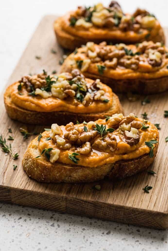 Pumpkin whipped feta crostini topped with walnuts, thyme, and honey for a simple fall party appetizer.