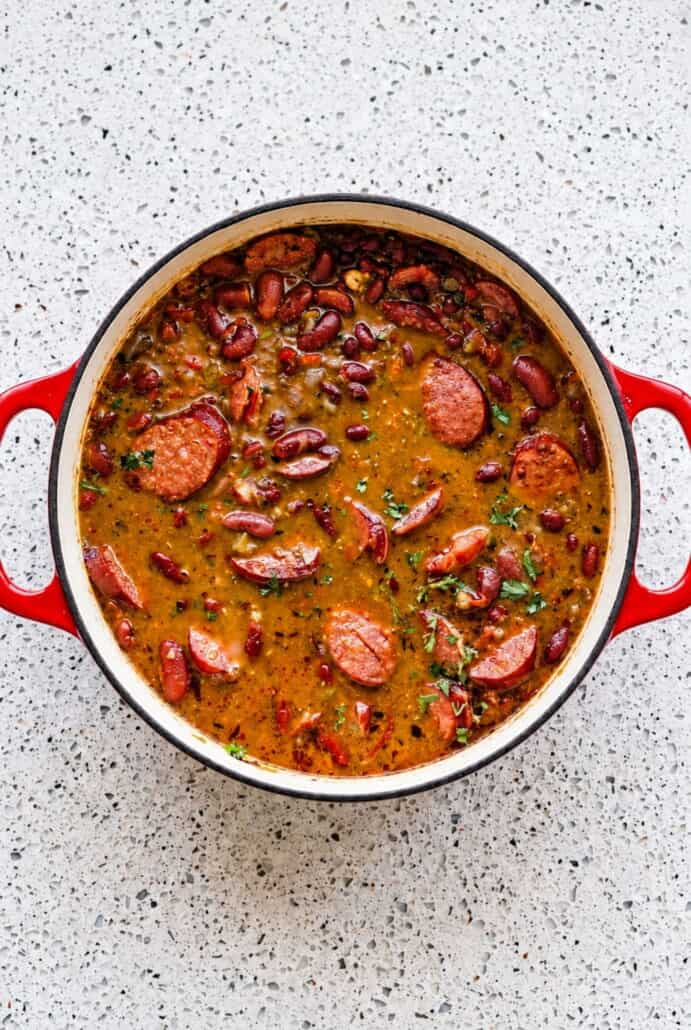 Red beans and Andouille sausage simmering in a pot, showing the savory mixture before serving with rice.