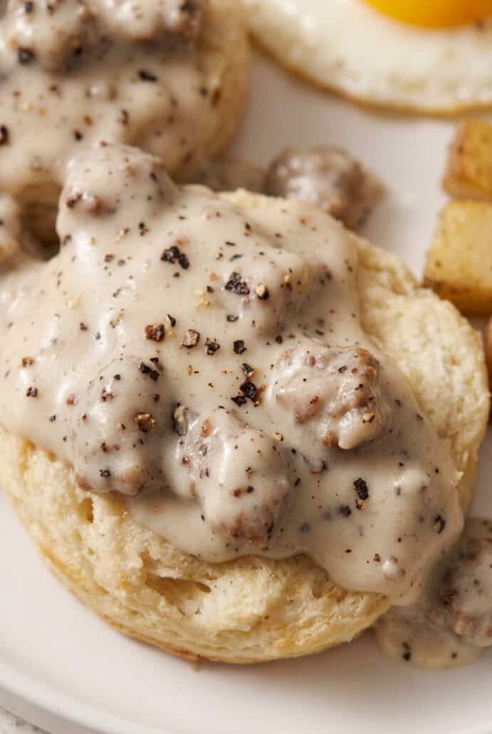 Creamy sausage gravy with black pepper served over a fluffy biscuit for an easy breakfast.