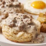Biscuits topped with creamy sausage gravy and black pepper, served with egg and breakfast potatoes.