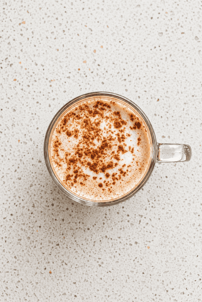 Top view of creamy vanilla cinnamon milk tea sprinkled with ground cinnamon.